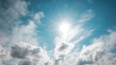 il sole contornato di nuvole in un cielo azzurro chiaro