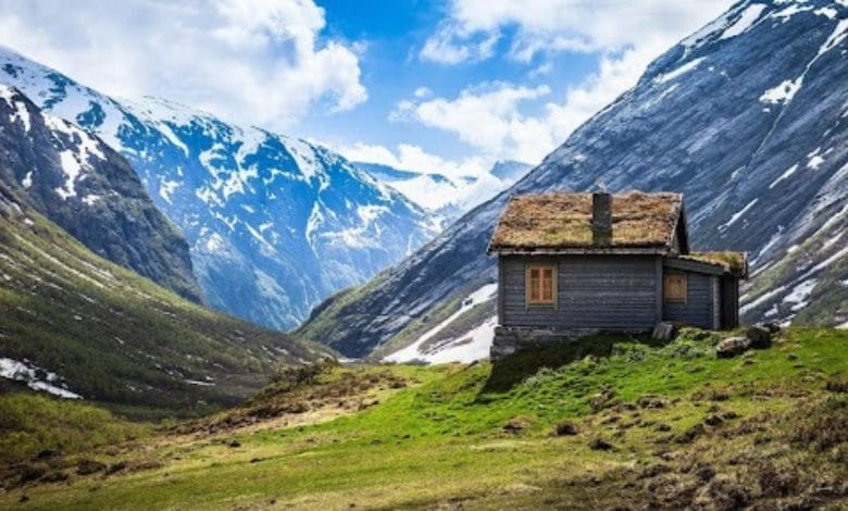 una casa di pietra e legno tra le vallate verdi e innevate della norvegia, simboleggia il friluftsliv