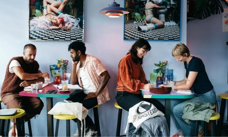 quattro ragazzi, in coppia, leggono e parlano sorridendo nel locale offline club di amsterdam