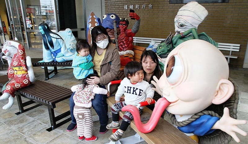 la statua di uno yokai rosso su una pankina di fukusaki, città giapponese