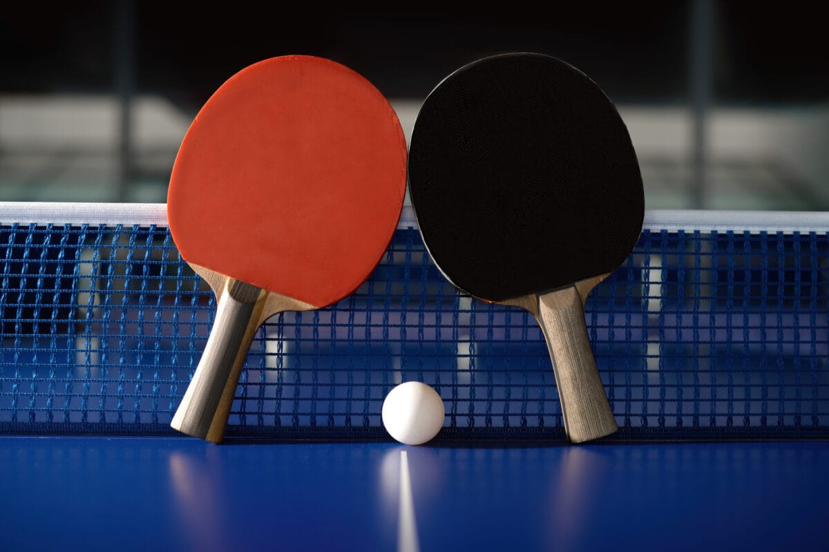 racchetta rossa e nera da ping pong su tavolo da gioco con pallina bianca al centro