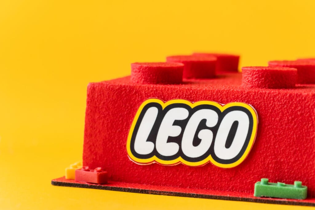 Logo della lego su un mattoncino in feltro rosso. il background è giallo