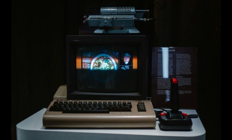 una console commodore 64 completa di schermo e joystick su un tavolo di color grigio in penombra