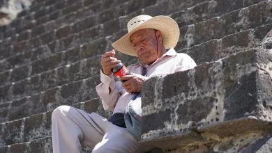 un uomo messicano che guarda una bottiglia di coca cola seduto su un gradino di pietra