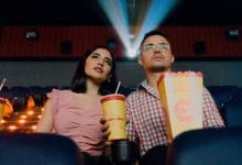 due persone, uomo e donna, che guardano la proiezione di un film al cinema con popcorn e bibita