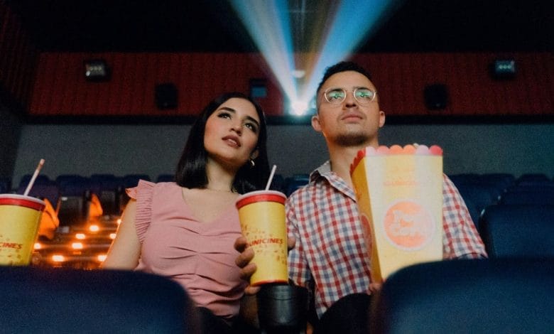 due persone, uomo e donna, che guardano la proiezione di un film al cinema con popcorn e bibita