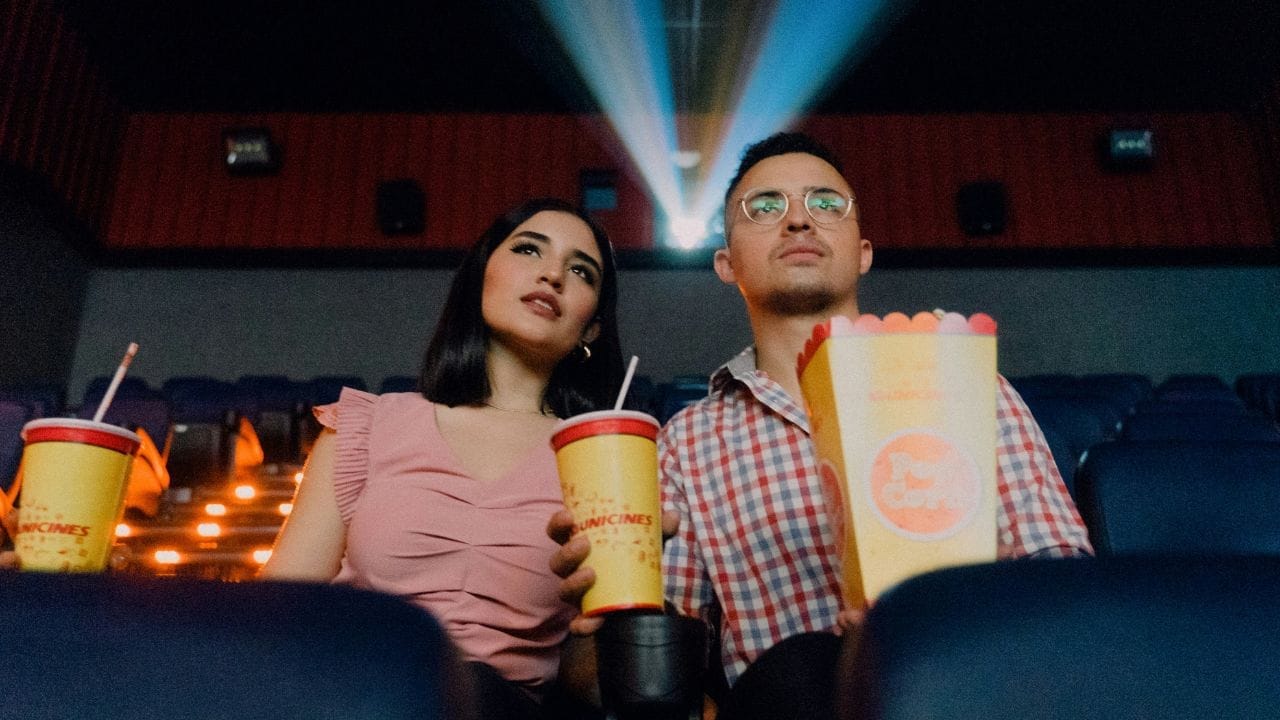 due persone, uomo e donna, che guardano la proiezione di un film al cinema con popcorn e bibita