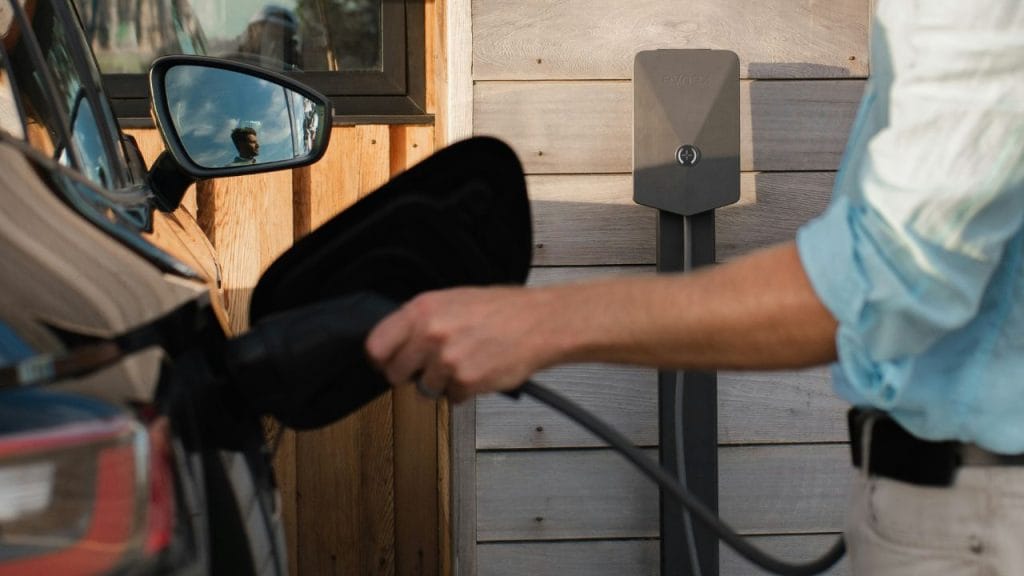 un uomo che carica la propria auto elettrica tramite una colonnina di ricarica 