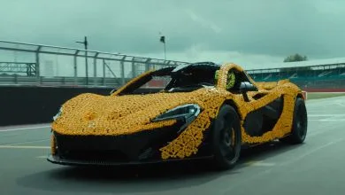 una mclaren fatta completamente di lego, colore giallo, che sfreccia sul circuito di silverstone