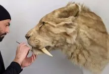 L'artista Ami Zarug a lavoro sulla sua opera d'arte che ritrae uno Smilodon