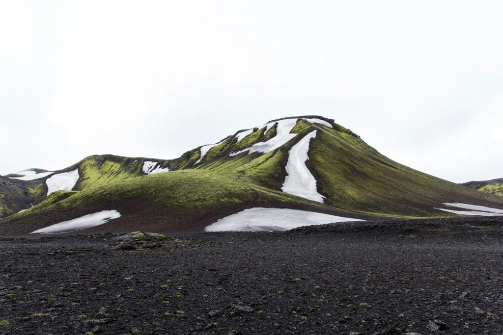 una montagna verde di erba in un paesaggio ghiacciato islandese