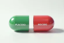 una pillola verde e rossa divisa a metà con scritto placebo e nocebo