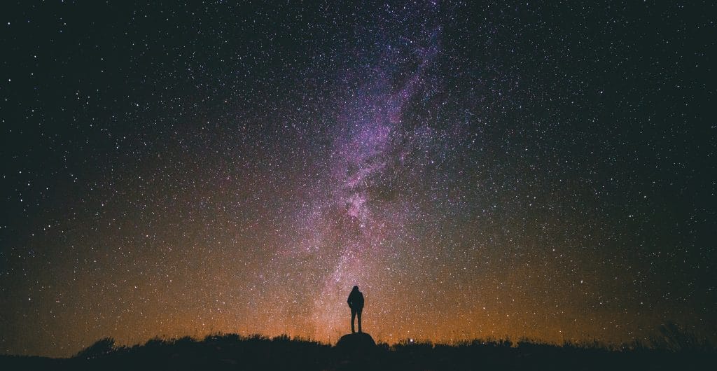 um homem olhando para o céu estrelado quase como se estivesse procurando formas de vida extraterrestres