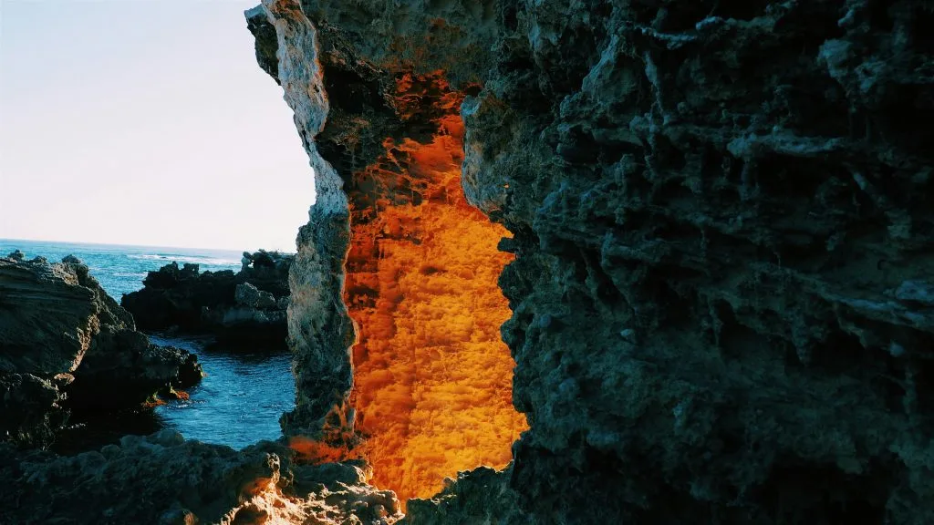 l'entrata di una caverna illuminata da dentro con mare in background