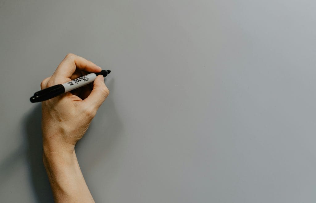 una mano sinistra che scrive con un pennarello