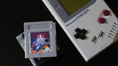 un game boy di prima generazione con la cartuccia gioco di tetris su sfondo nero