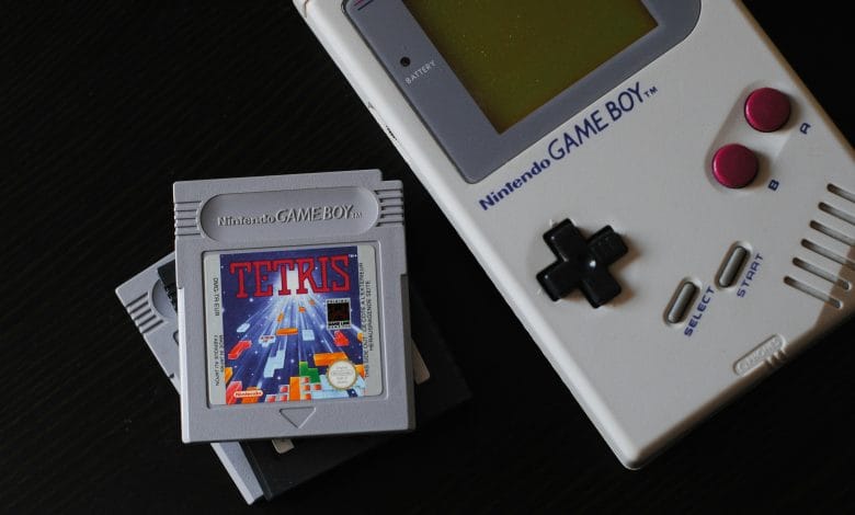 un game boy di prima generazione con la cartuccia gioco di tetris su sfondo nero