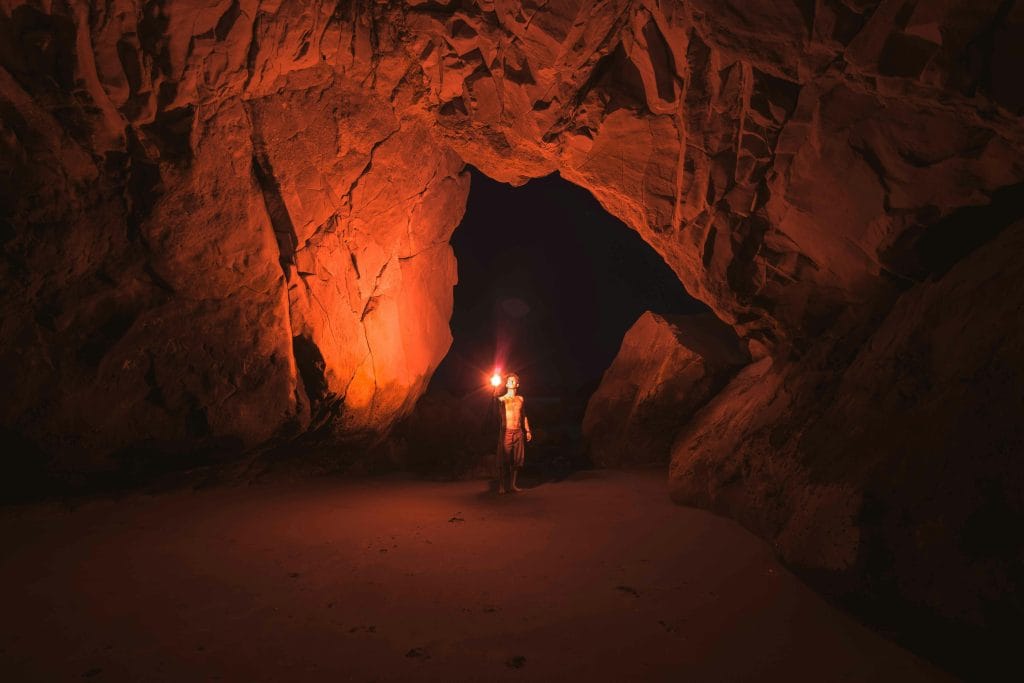 Un uomo con una torcia che esplora una grotta buia